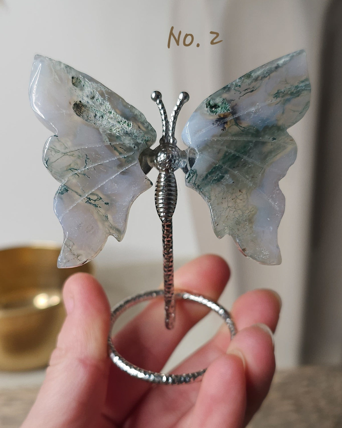 Moss Agate crystal butterfly wings on a stand with natural green moss-like inclusions. A nature-inspired decorative piece and meaningful gift for new beginnings.