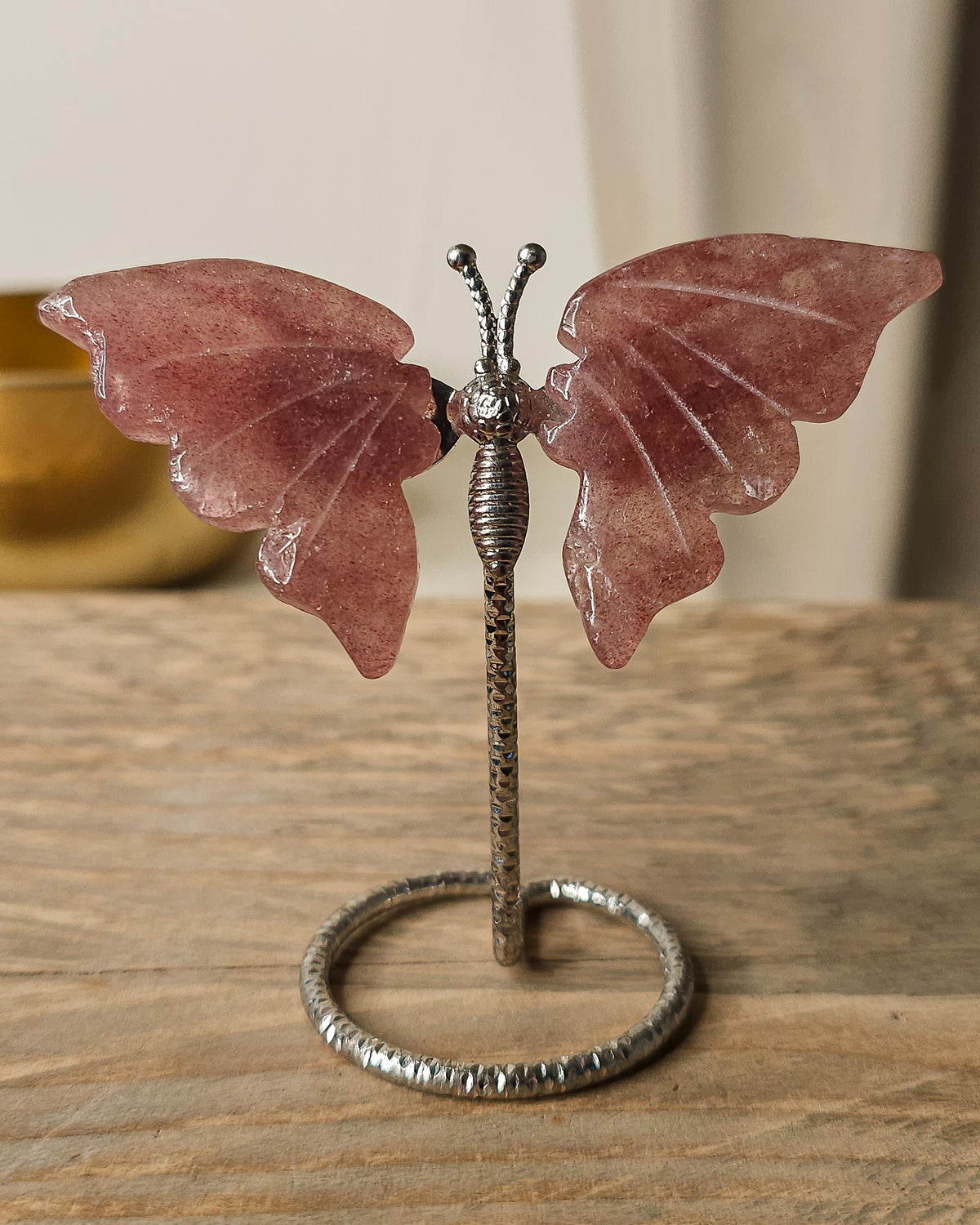 Strawberry Quartz butterfly carving on a silver metal stand, featuring soft rosy pink tones and delicate natural inclusions.
