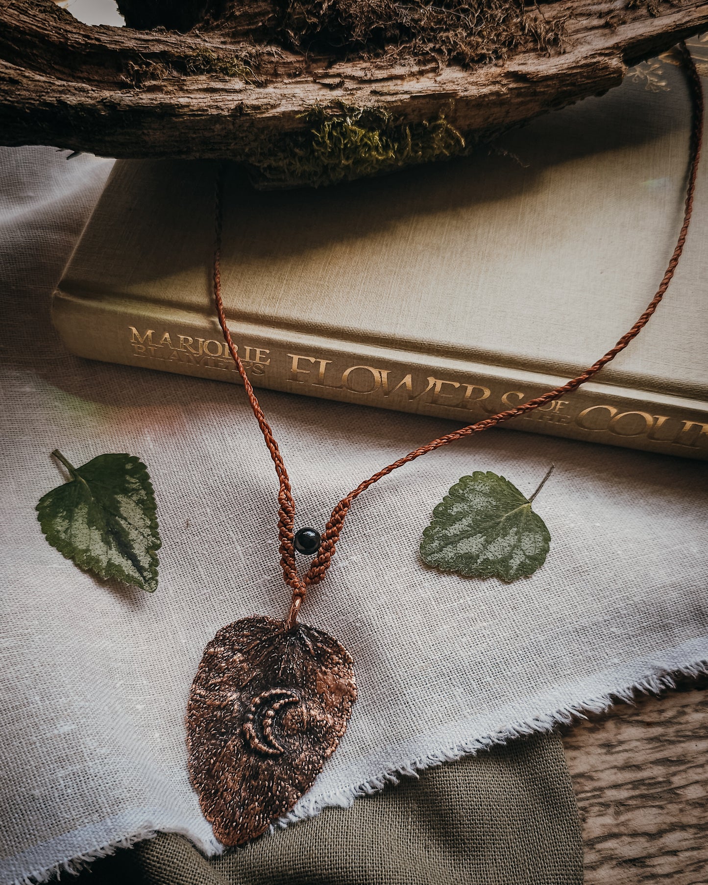 Side view of copper electroformed dead nettle leaf pendant on braided adjustable cord.