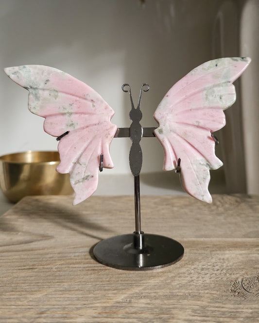 Pink Opal butterfly wings carved from natural pink opal, displayed on a black metal stand, showing soft pink and creamy tones.