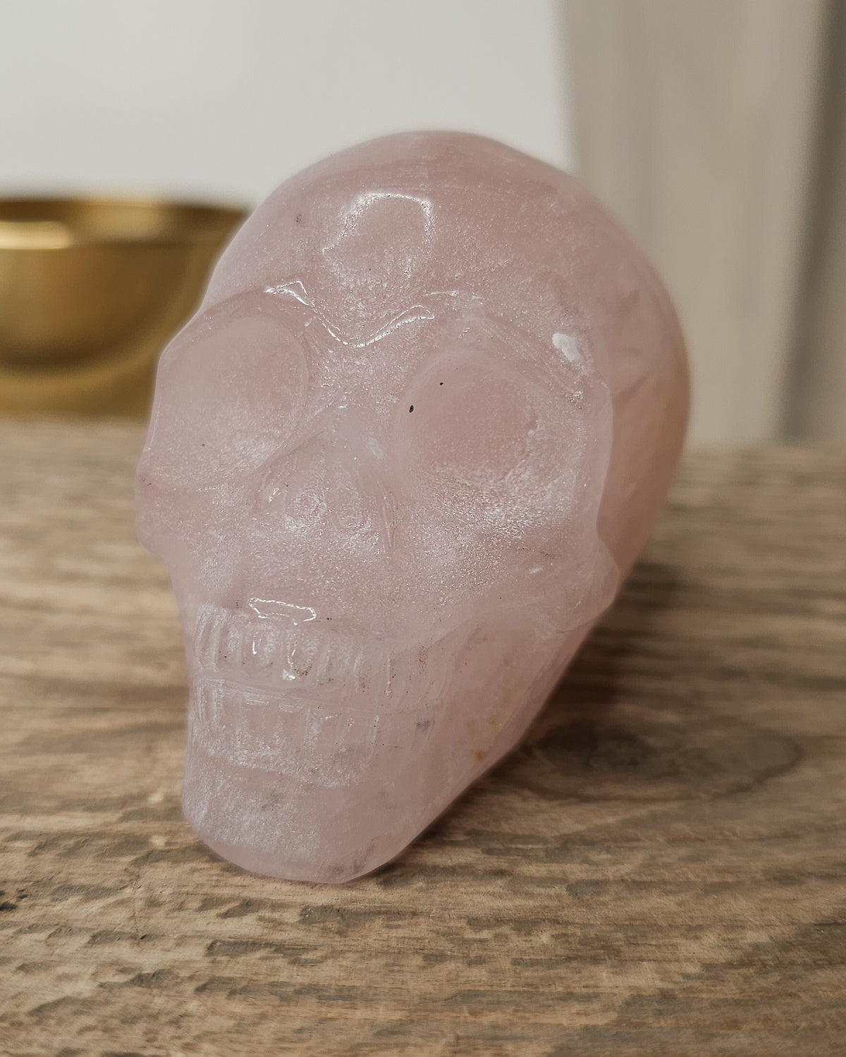 Rose Quartz crystal skull with natural red Hematite inclusions, showing soft pink tones and a reddish patch at the back.