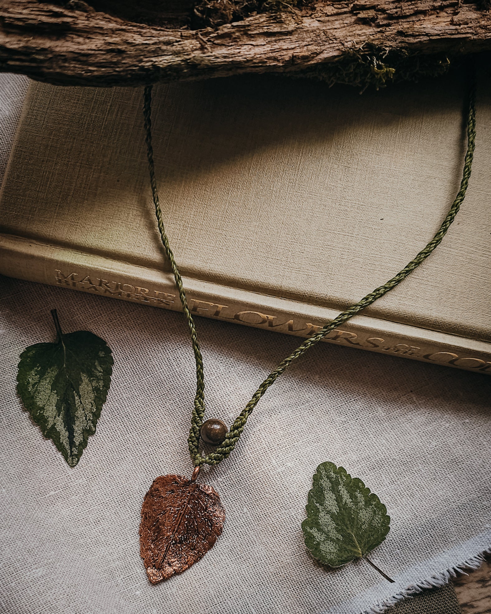 Side view of copper electroformed dead nettle leaf pendant with Brown Jasper bead on a braided adjustable cord.