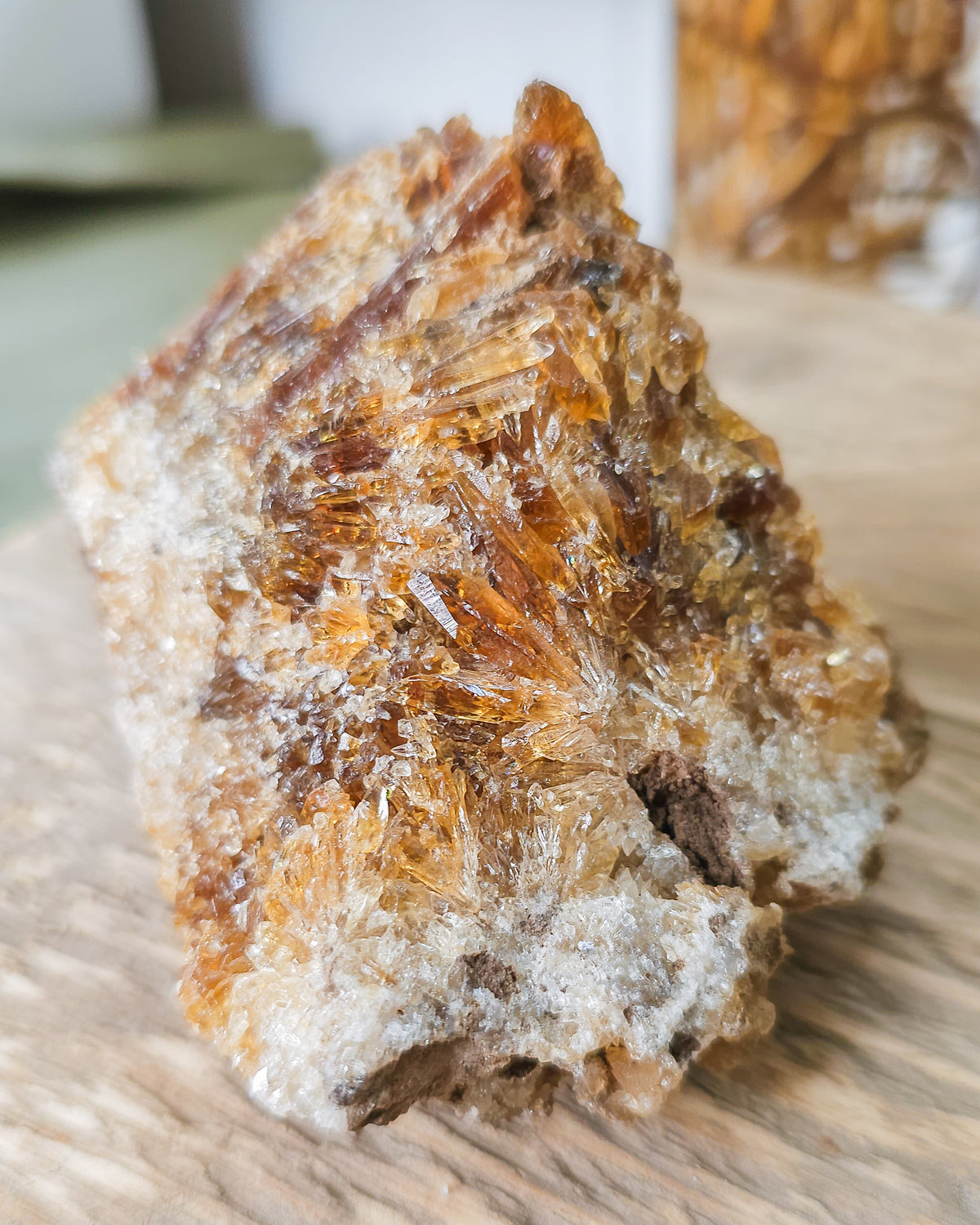 Mineral Amber Calcite specimen on a wooden surface with a blurred indoor background