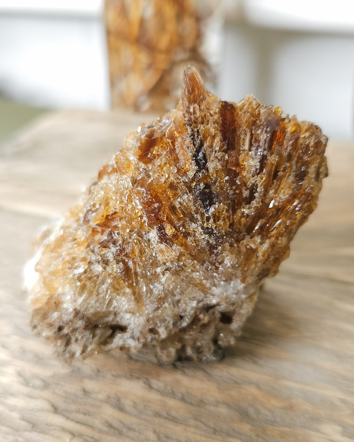 Mineral Amber Calcite specimen on a wooden surface with a blurred indoor background