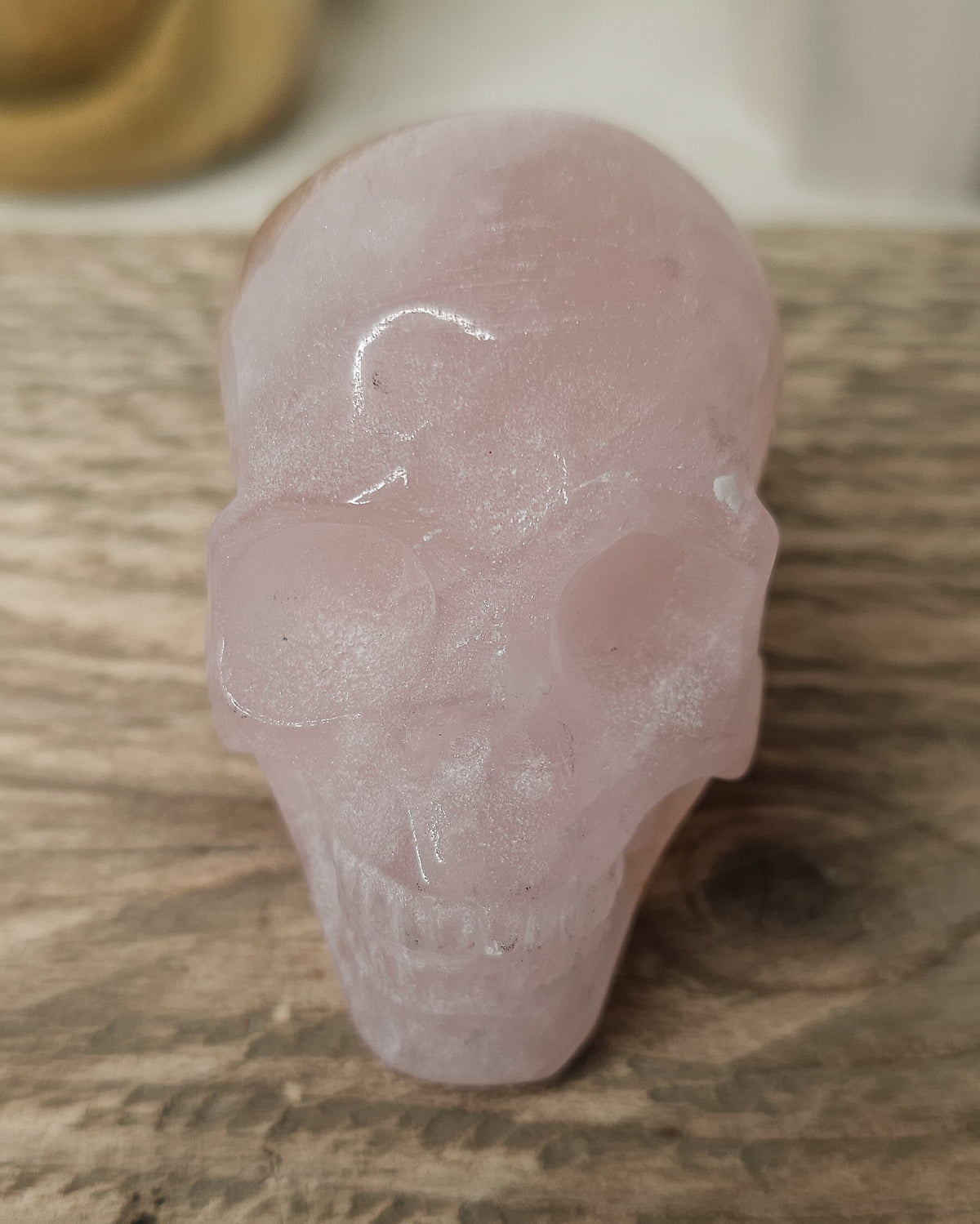 Rose Quartz crystal skull with natural red Hematite inclusions, showing soft pink tones and a reddish patch at the back.