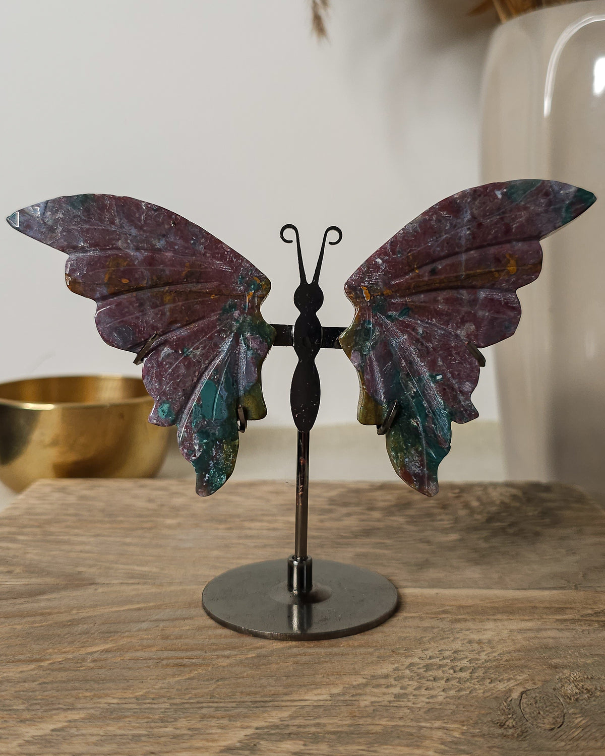 Jasper butterfly wings on a black metal stand, featuring earthy burgundy, green and golden natural patterns.