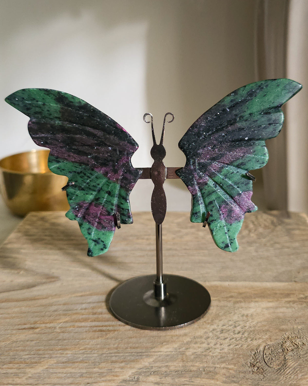 Ruby in Zoisite butterfly wings with fluorescent Ruby inclusions on a black metal stand, glowing vivid pink-red under UV light.