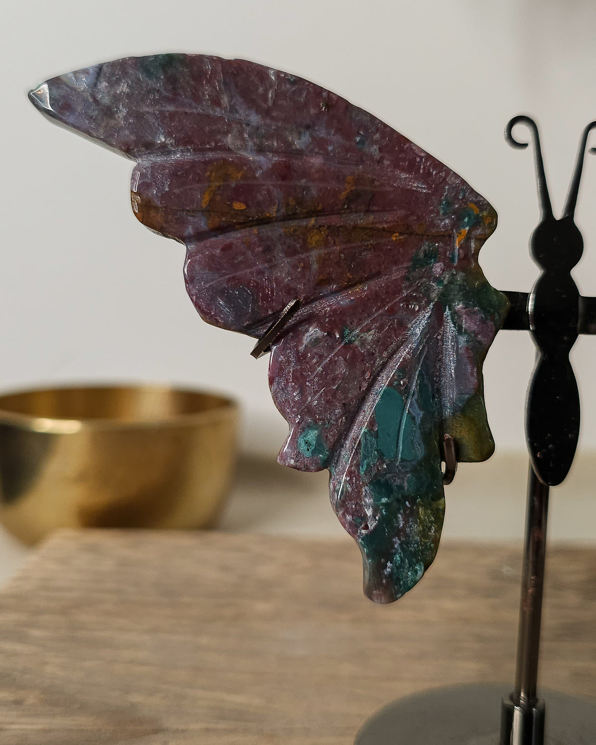 Jasper butterfly wings on a black metal stand, featuring earthy burgundy, green and golden natural patterns.