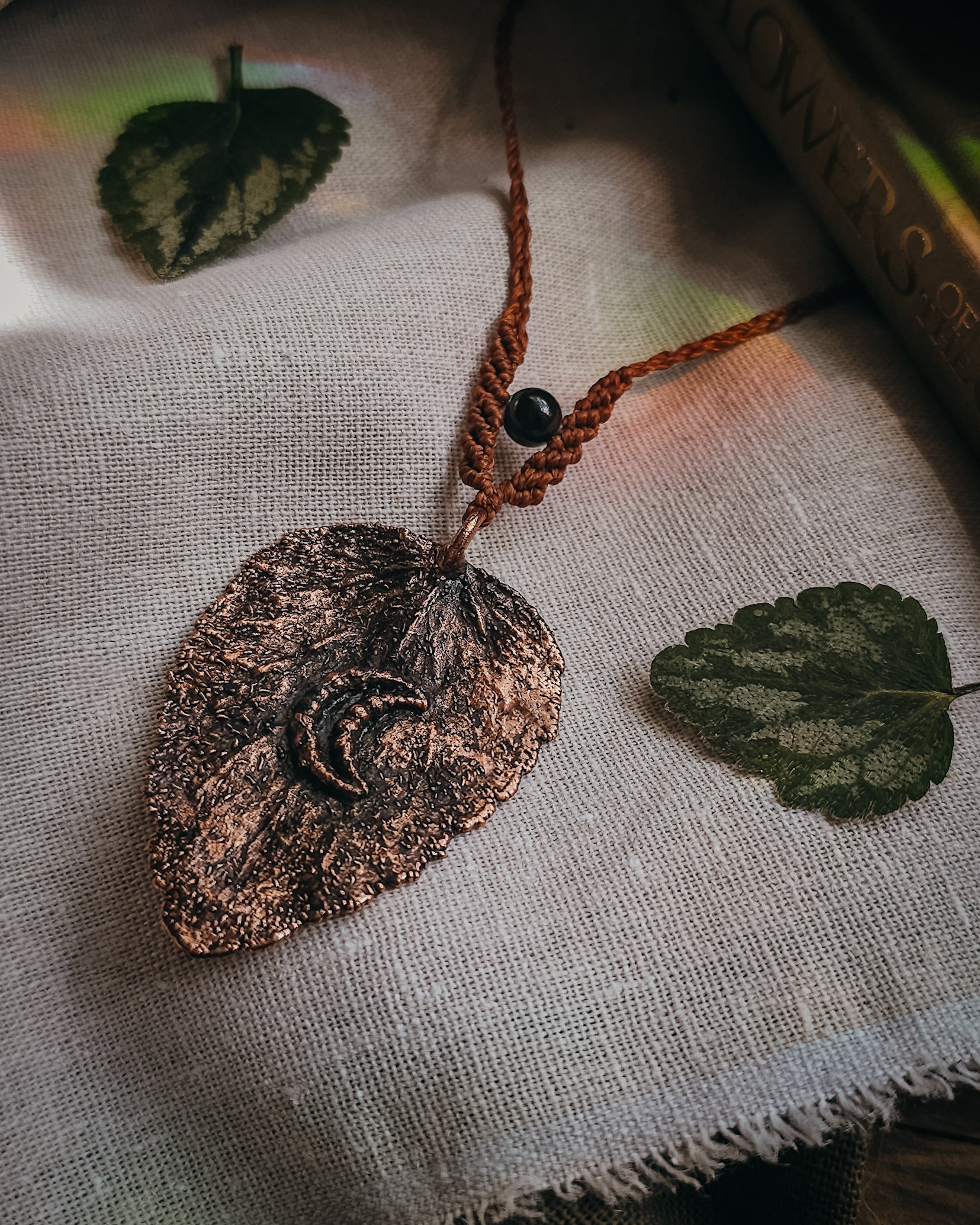 Handcrafted copper electroformed dead nettle leaf necklace with Golden Sheen Obsidian and handwoven micromacramé detailing.
