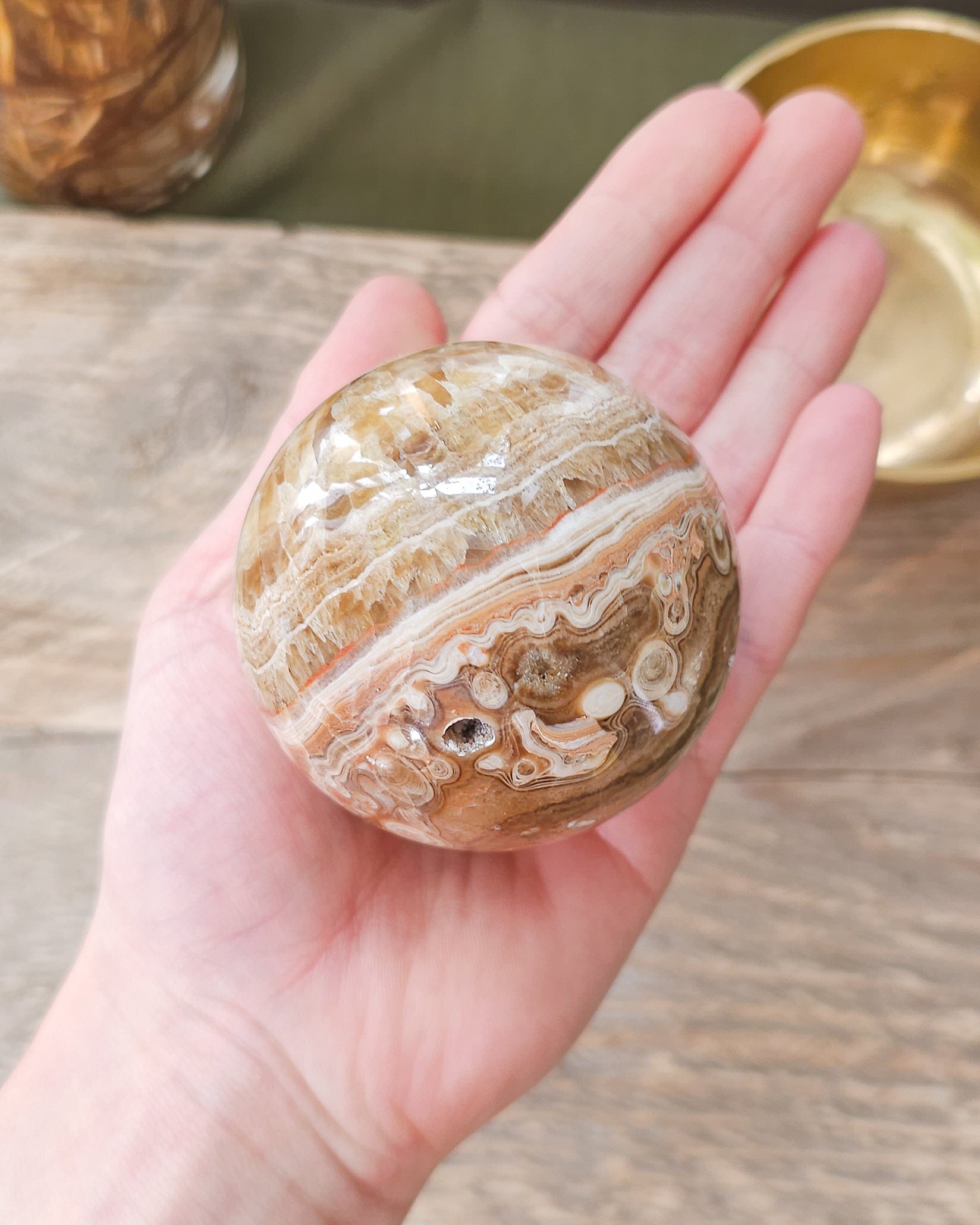 Handheld Chocolate Calcite sphere with natural druzy crystals and intricate orbicular formations.