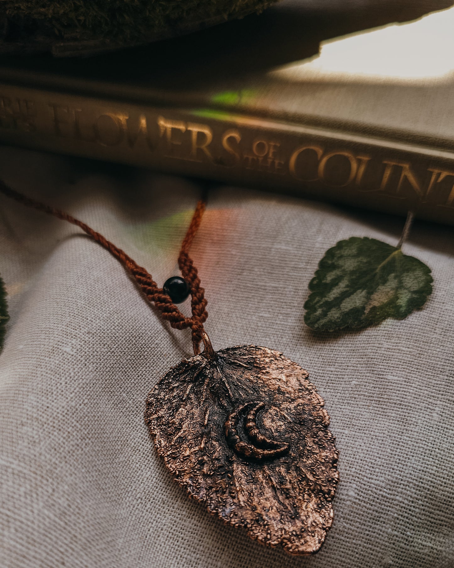 Close-up of Nettle Spirit Scottish Botanical Amulet showing the intricate leaf veins captured in copper and Golden Sheen Obsidian bead.