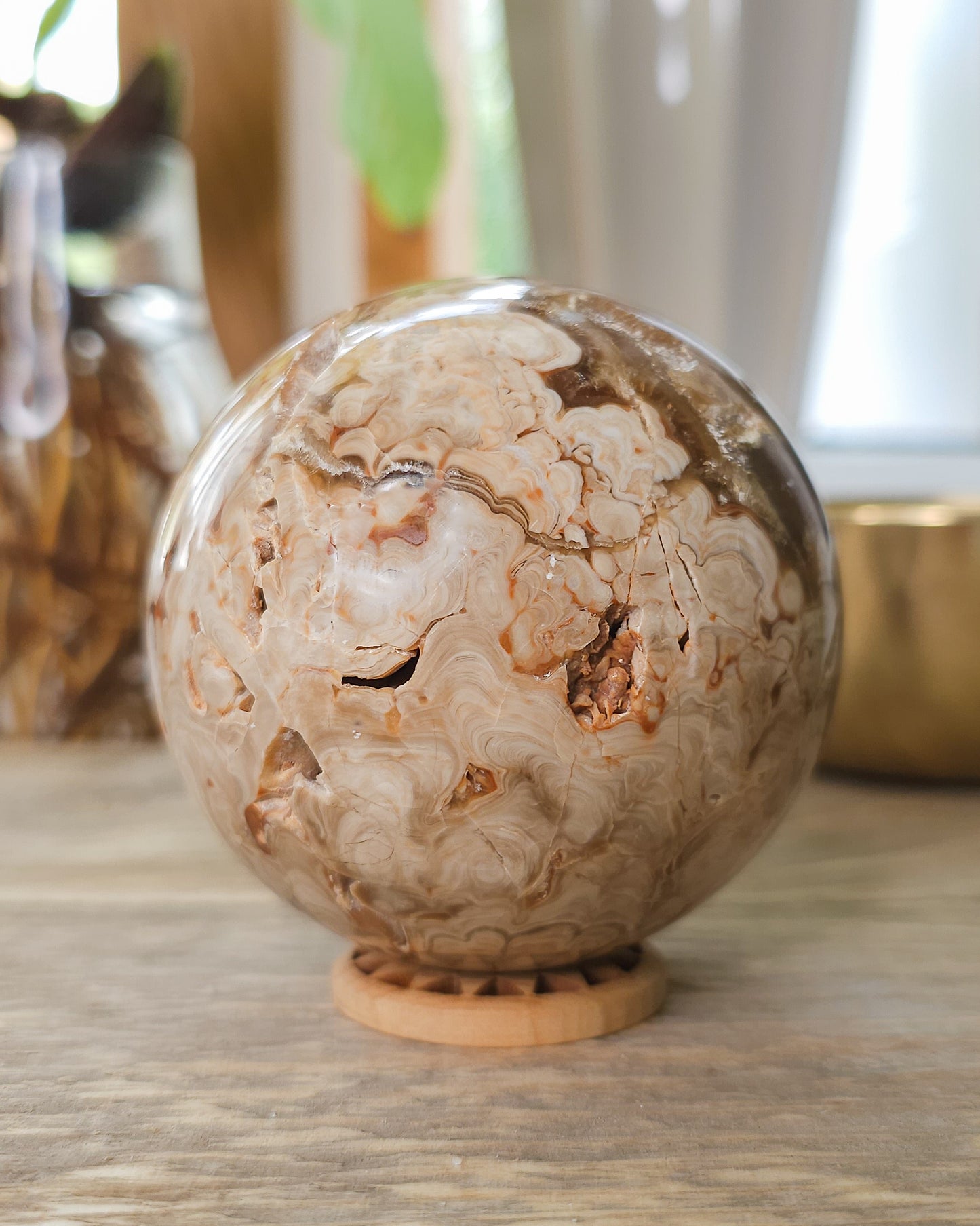 Polished Chocolate Calcite sphere with orbicular patterns and raw cavity.