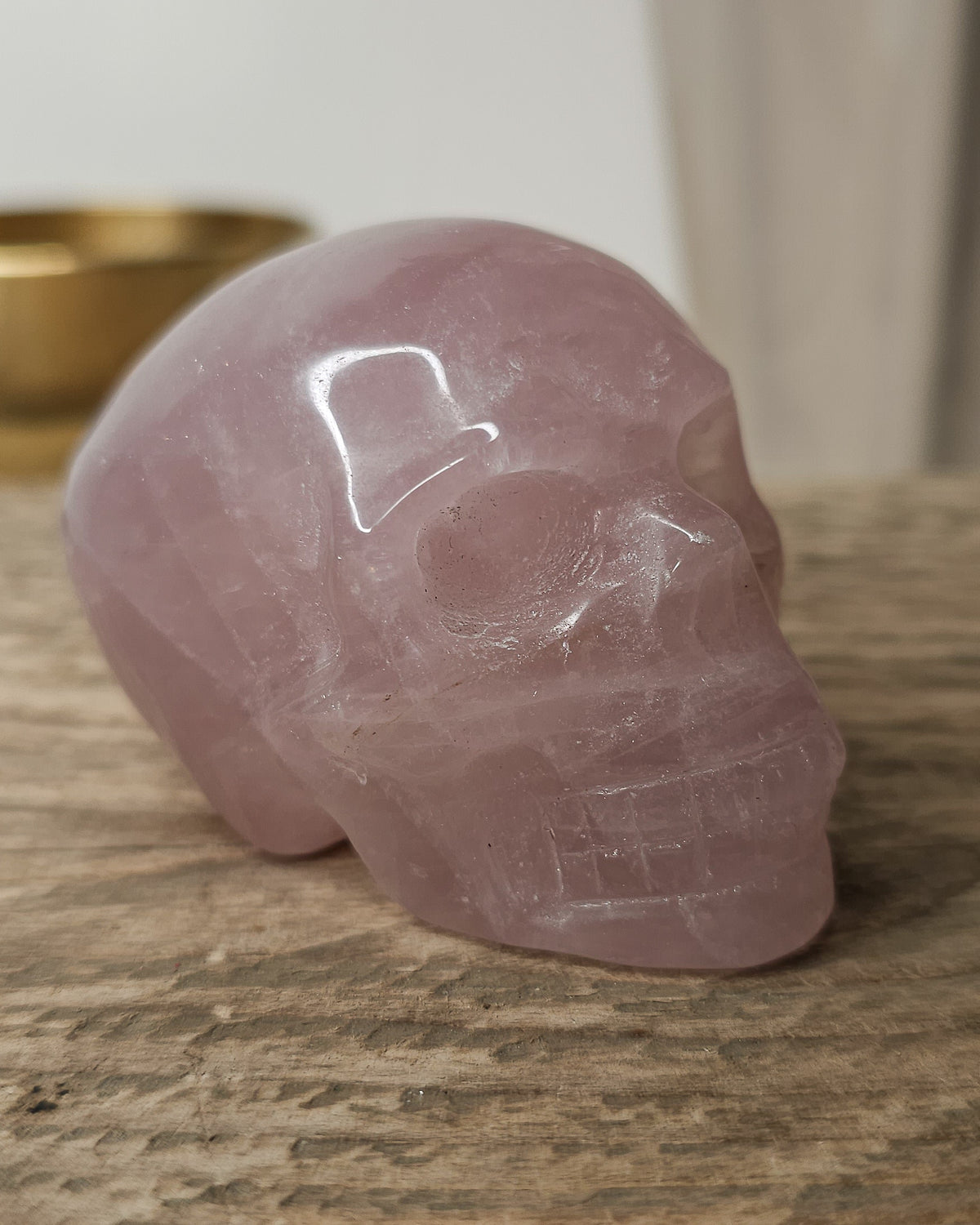 Rose Quartz crystal skull carving with soft pink tones and natural cloudy patterns, polished finish, displayed as a decorative crystal piece.