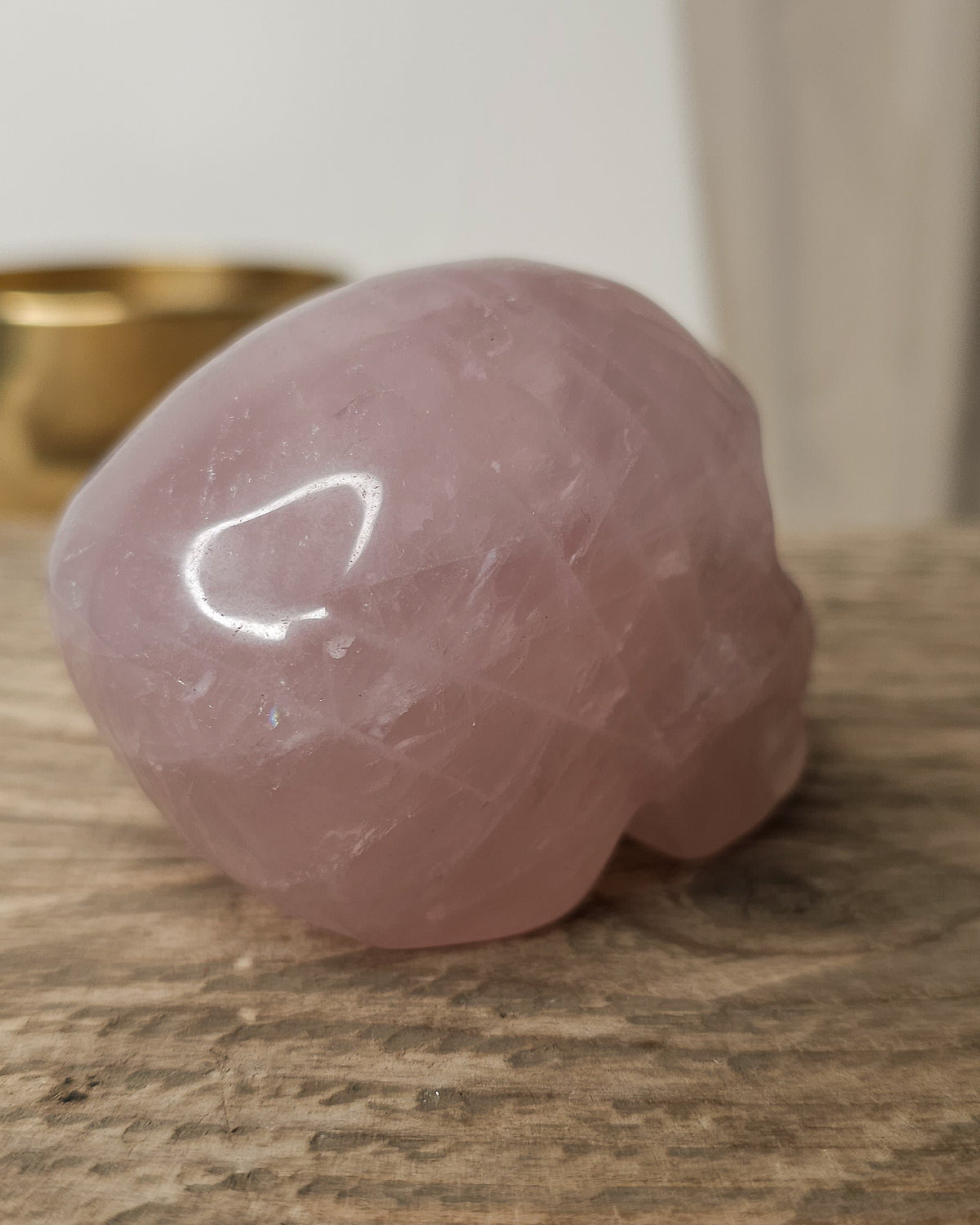 Rose Quartz crystal skull carving with soft pink tones and natural cloudy patterns, polished finish, displayed as a decorative crystal piece.