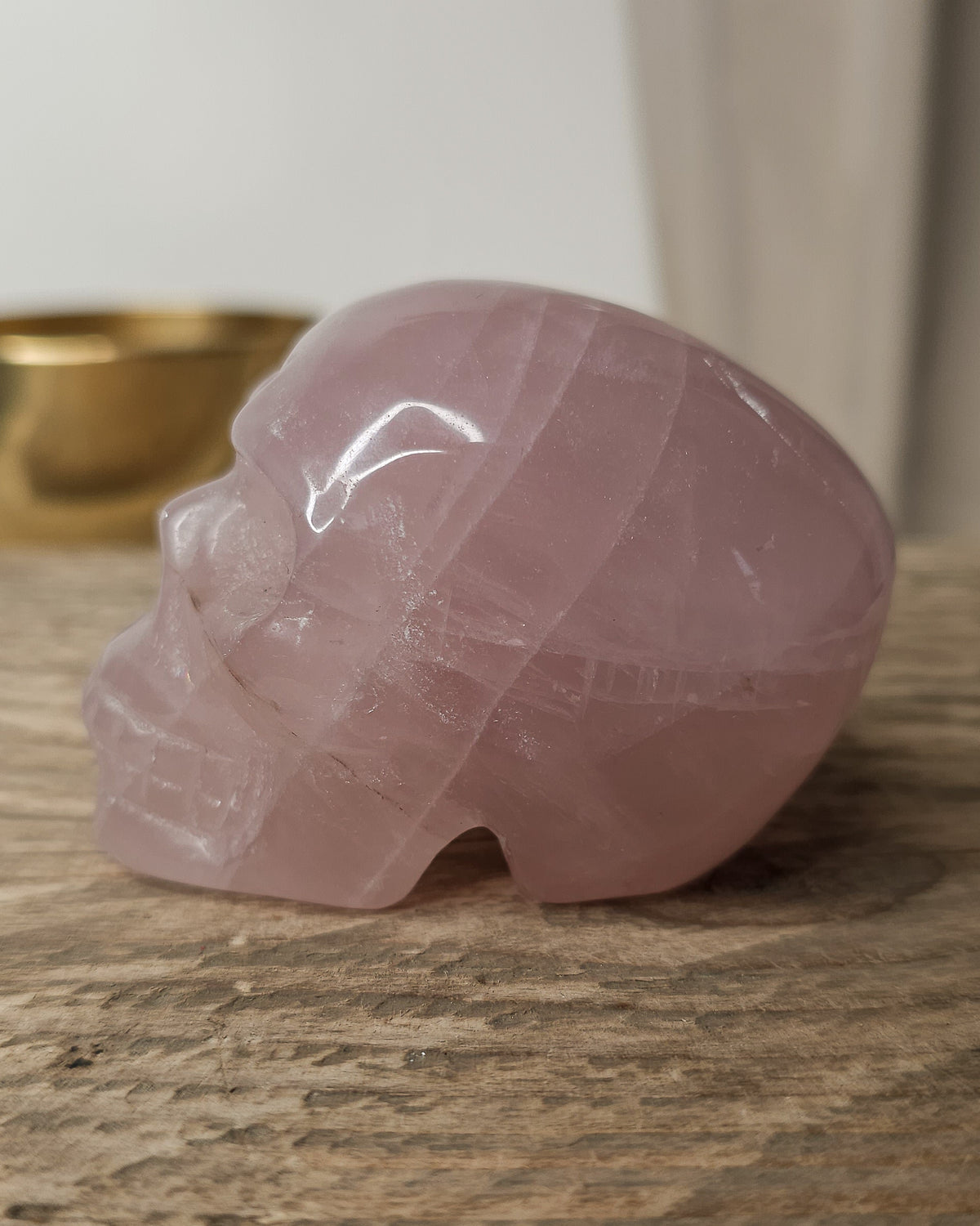 Rose Quartz crystal skull carving with soft pink tones and natural cloudy patterns, polished finish, displayed as a decorative crystal piece.