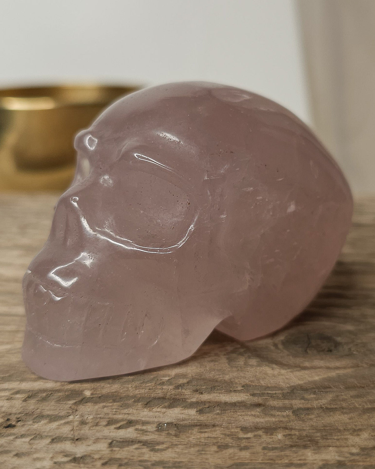 Rose Quartz crystal skull carving with soft pink tones and natural cloudy patterns, polished finish, displayed as a decorative crystal piece.