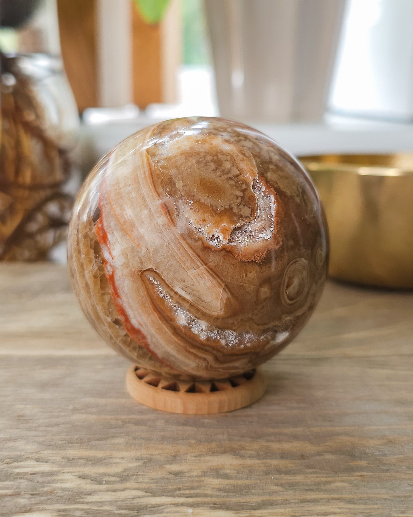 Polished Chocolate Calcite sphere with orbicular patterns and sparkling druzy cavity.