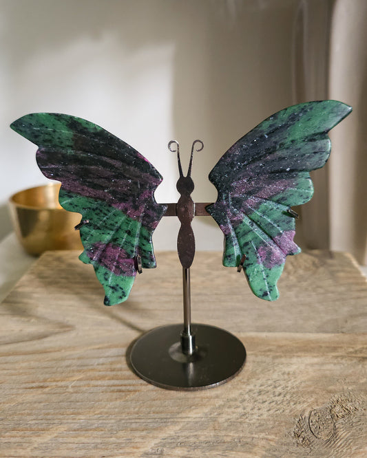 Ruby in Zoisite butterfly wings with fluorescent Ruby inclusions on a black metal stand, glowing vivid pink-red under UV light.
