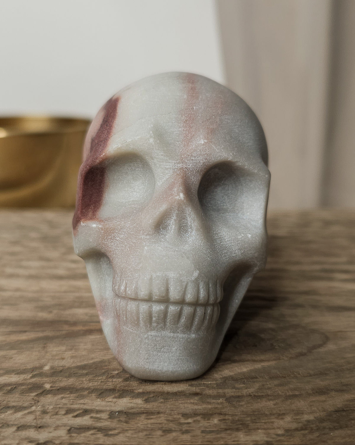 Mookaite crystal skull carving with natural burgundy, dusty pink, cream and grey patterns, polished finish and detailed teeth.