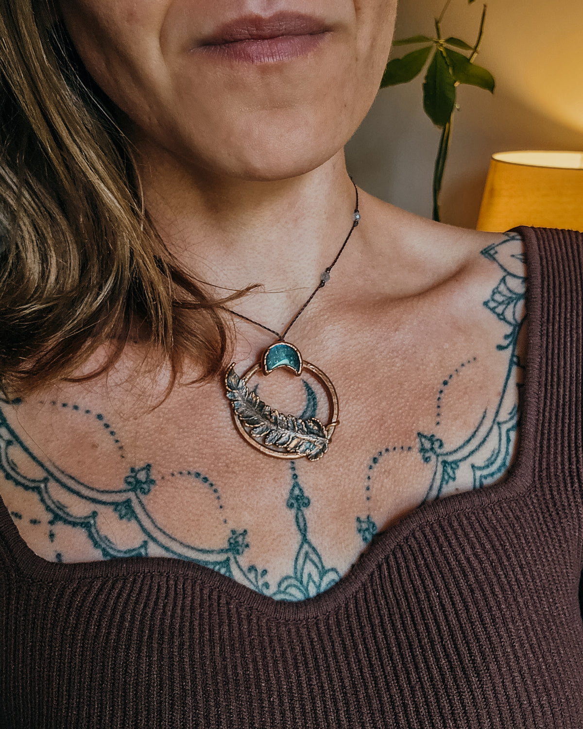 Handcrafted copper fern and Labradorite moon pendant worn on an adjustable cord necklace, showing scale and fit of the Scottish botanical amulet against the neckline.
