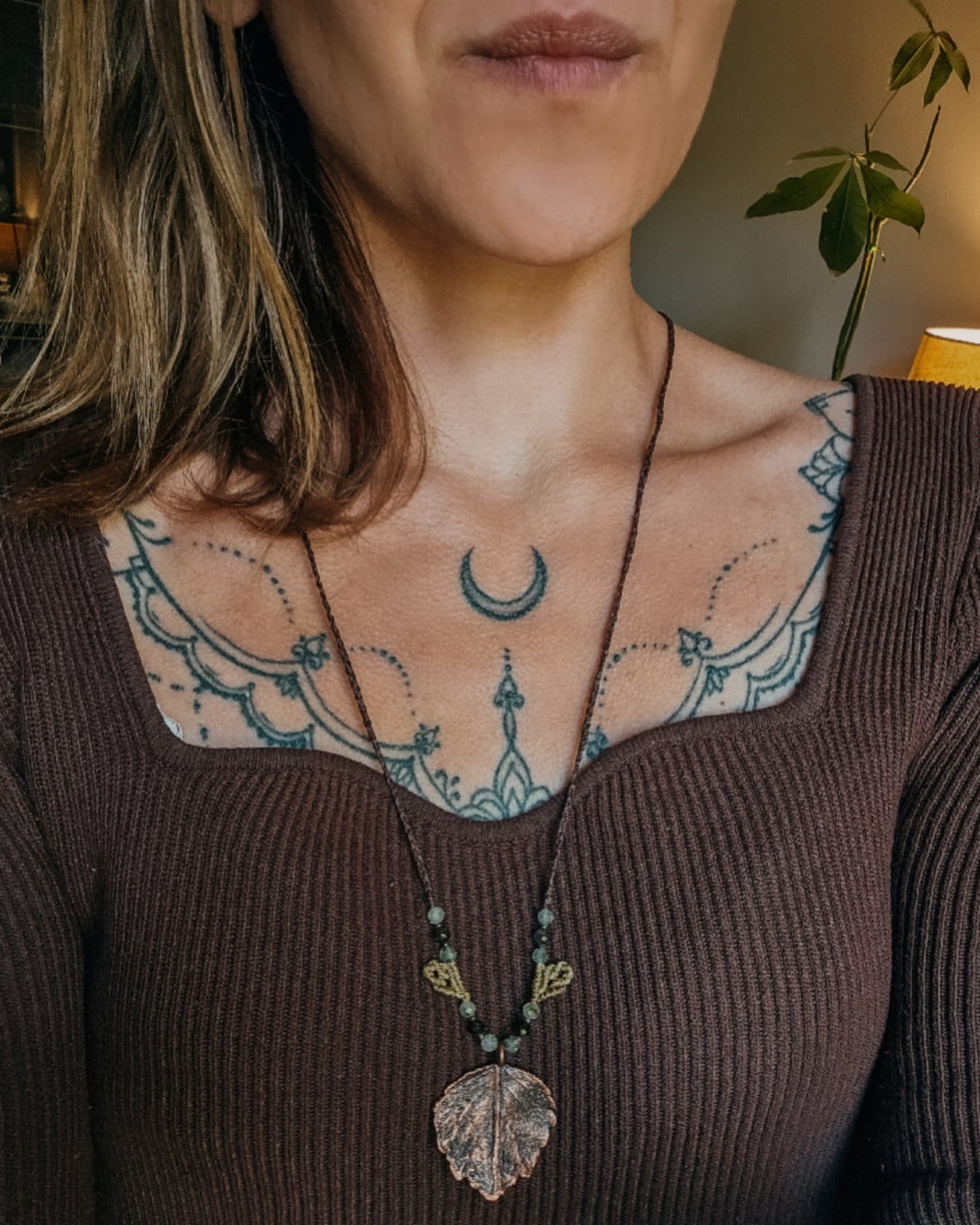 Woman wearing Nettle Spirit Scottish Botanical Amulet, a copper electroformed dead nettle leaf necklace featuring Prehnite with Epidote beads.