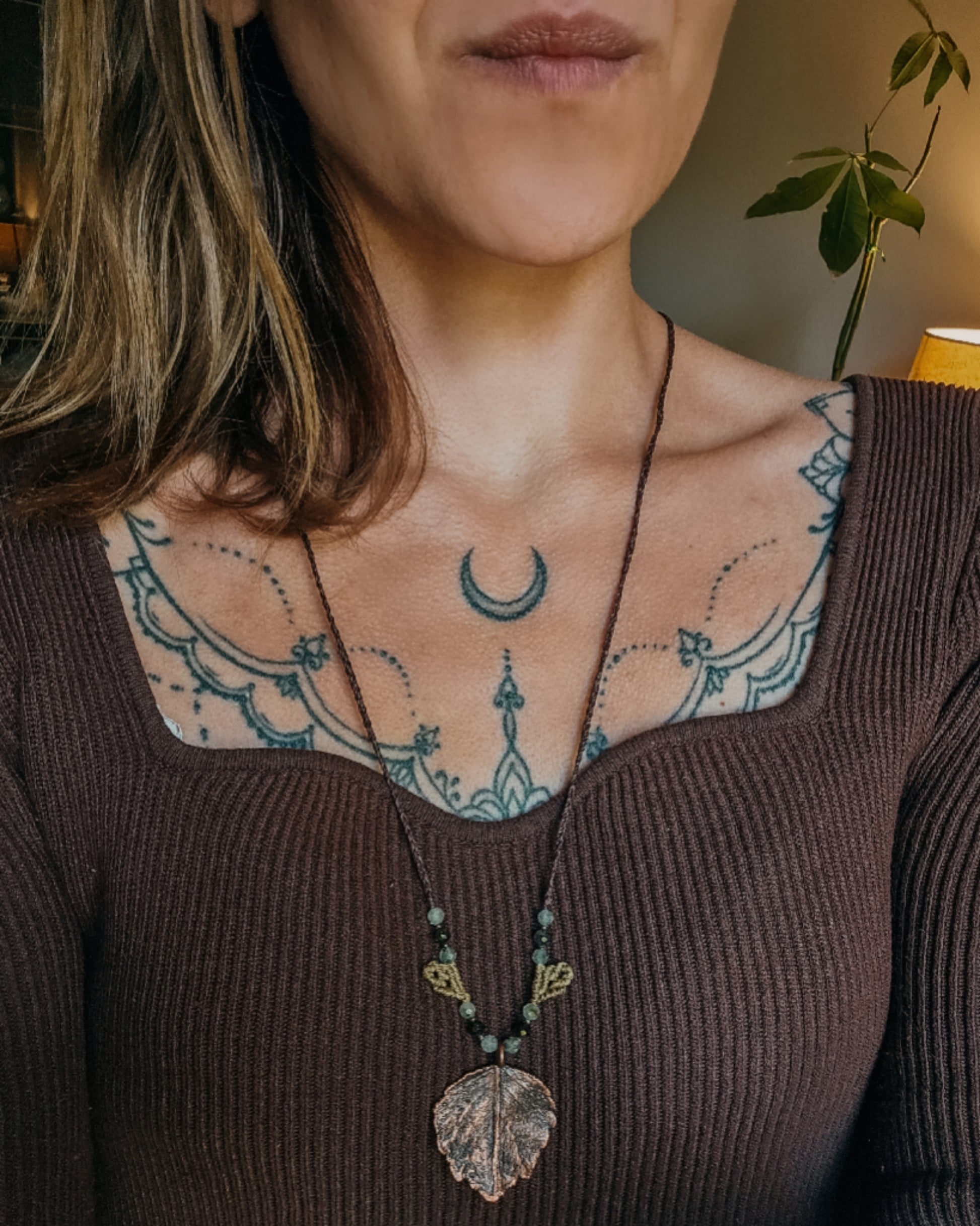 Woman wearing Nettle Spirit Scottish Botanical Amulet, a copper electroformed dead nettle leaf necklace featuring Prehnite with Epidote beads.