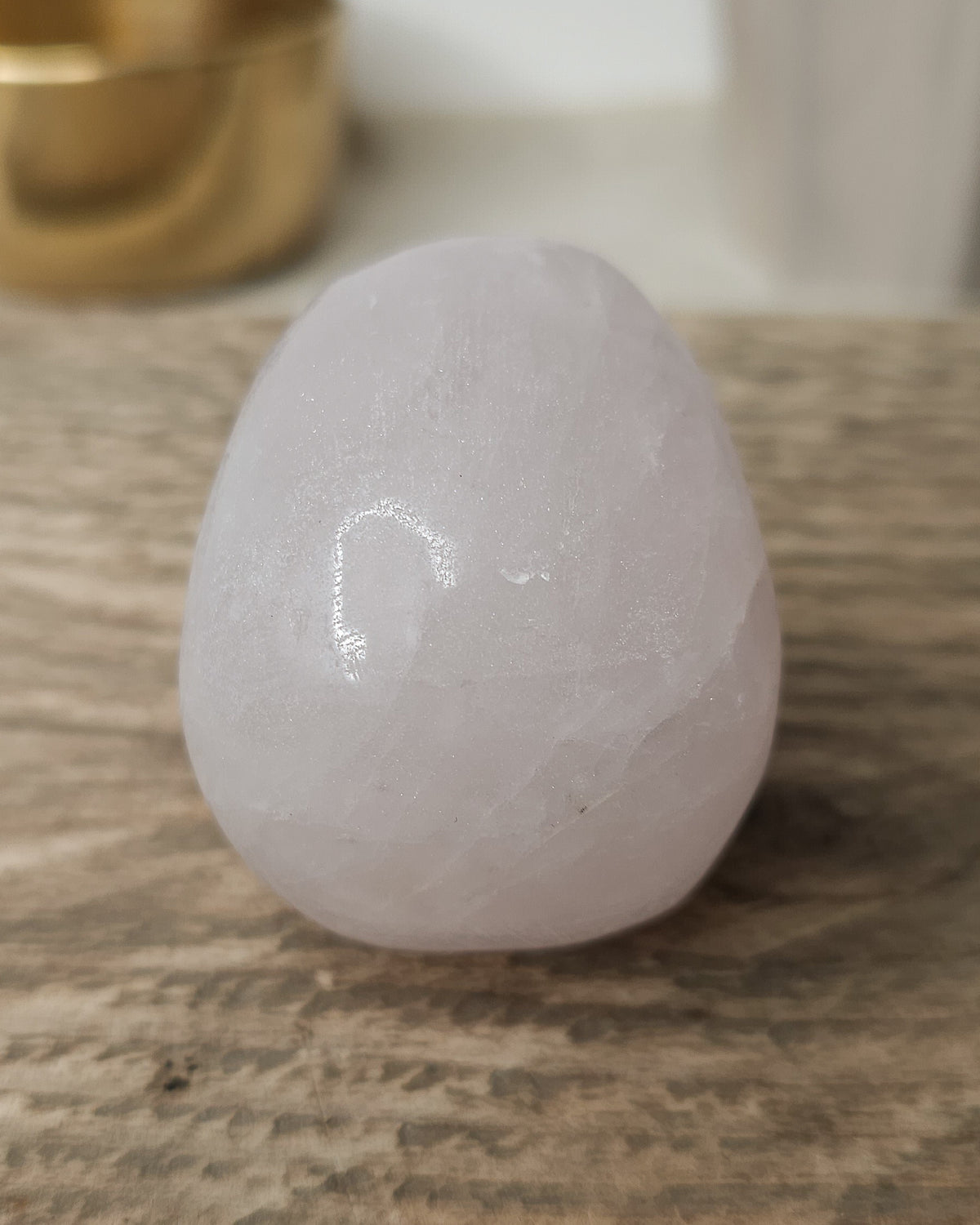 Rose Quartz crystal skull with natural red Hematite inclusions, showing soft pink tones and a reddish patch at the base.