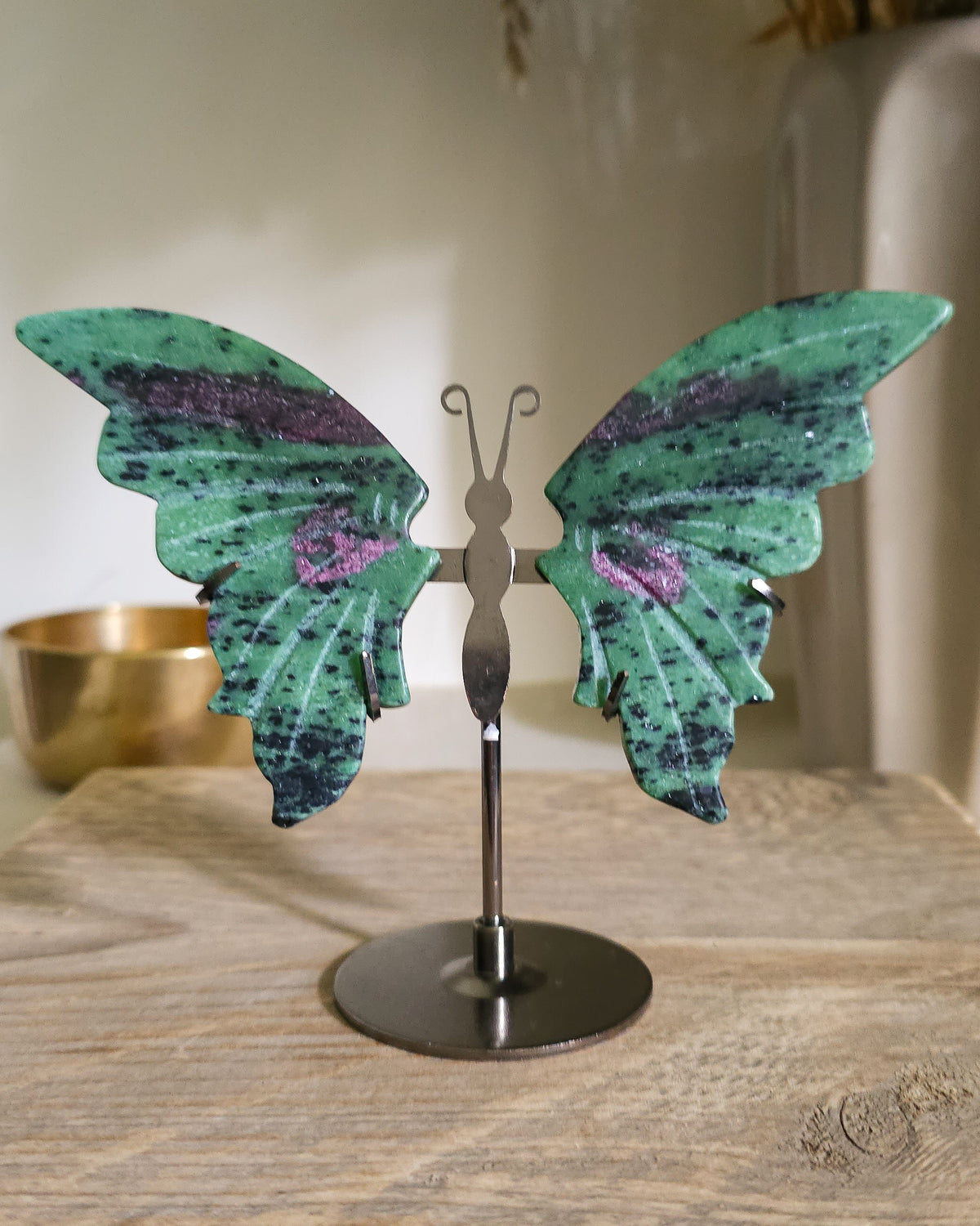Ruby in Zoisite butterfly wings with fluorescent Ruby inclusions on a black metal stand, glowing vivid pink-red under UV light.