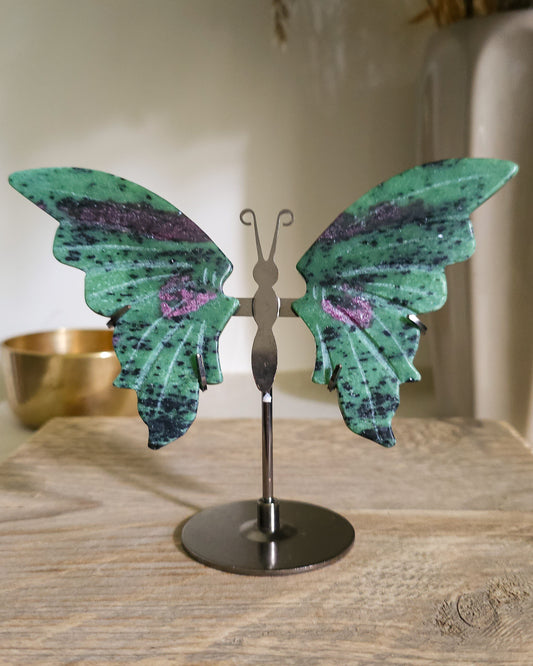 Ruby in Zoisite butterfly wings with fluorescent Ruby inclusions on a black metal stand, glowing vivid pink-red under UV light.