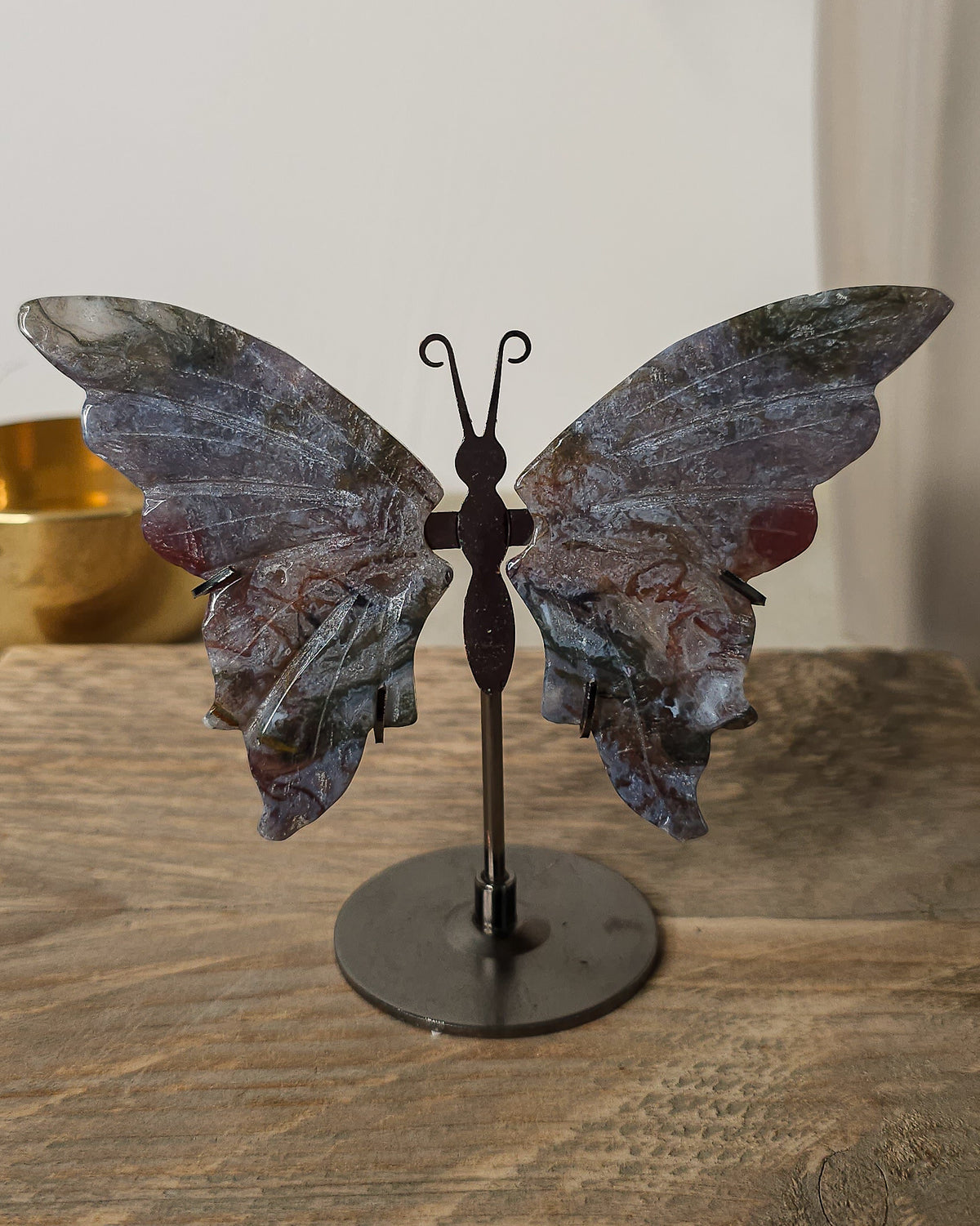 Moss Agate butterfly wings on a black metal stand, featuring natural grey, green, brown and reddish patterns.

