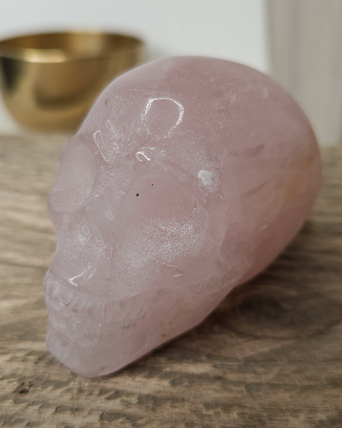 Rose Quartz crystal skull with natural red Hematite inclusions, showing soft pink tones and a reddish patch at the back.