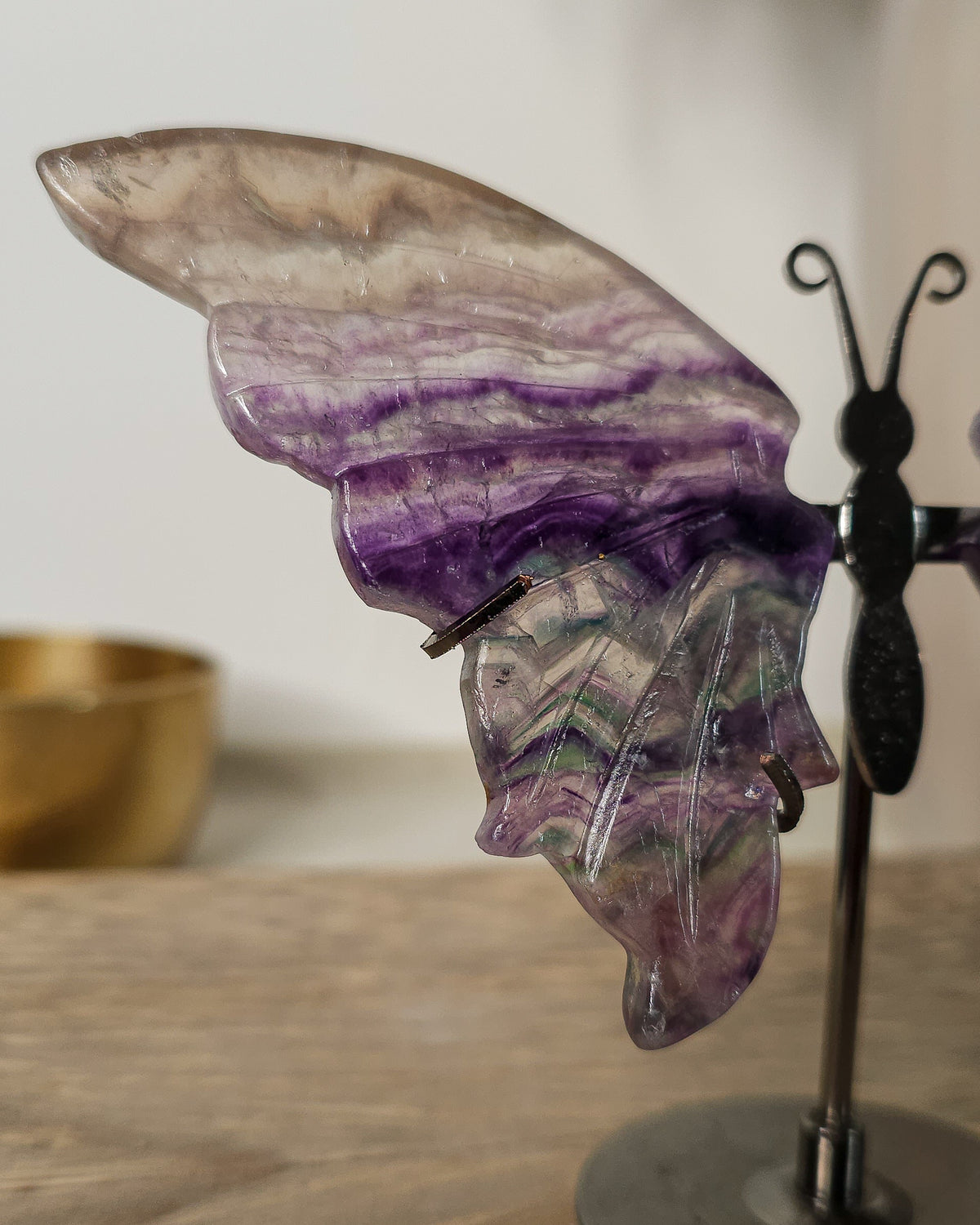 Fluorite crystal butterfly wings on a stand, with purple, green and golden tones. A beautiful display piece and meaningful gift for new beginnings.
