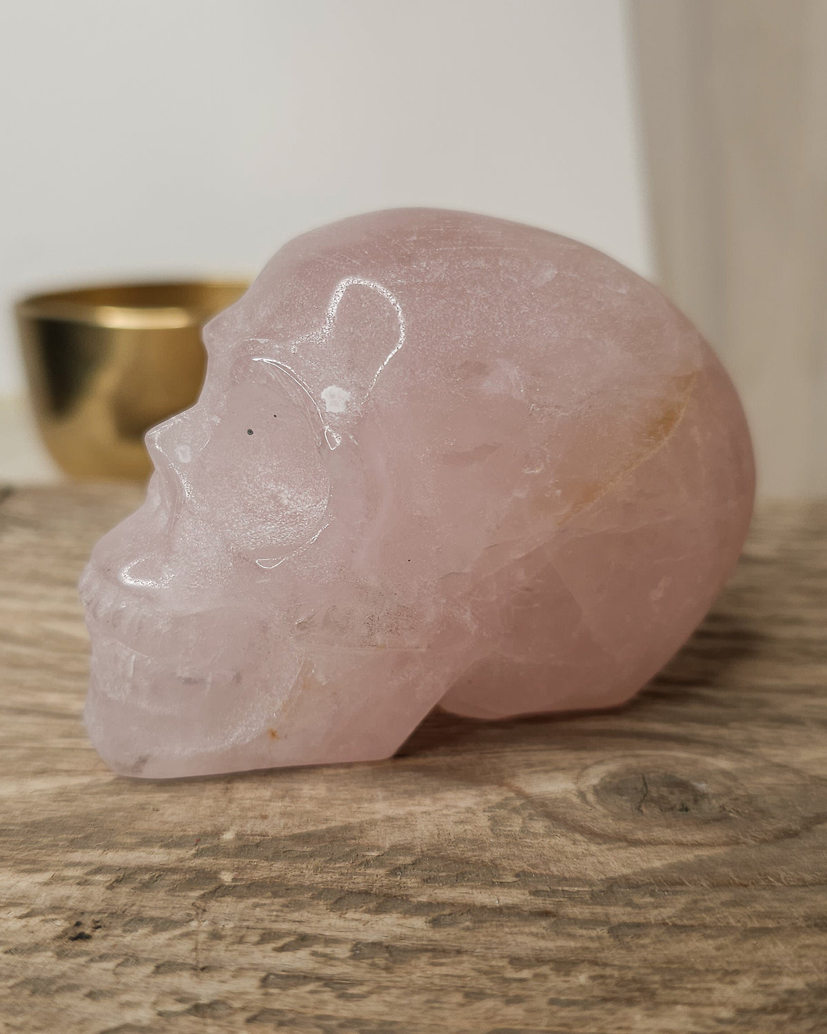 Rose Quartz crystal skull with natural red Hematite inclusions, showing soft pink tones and a reddish patch at the back.