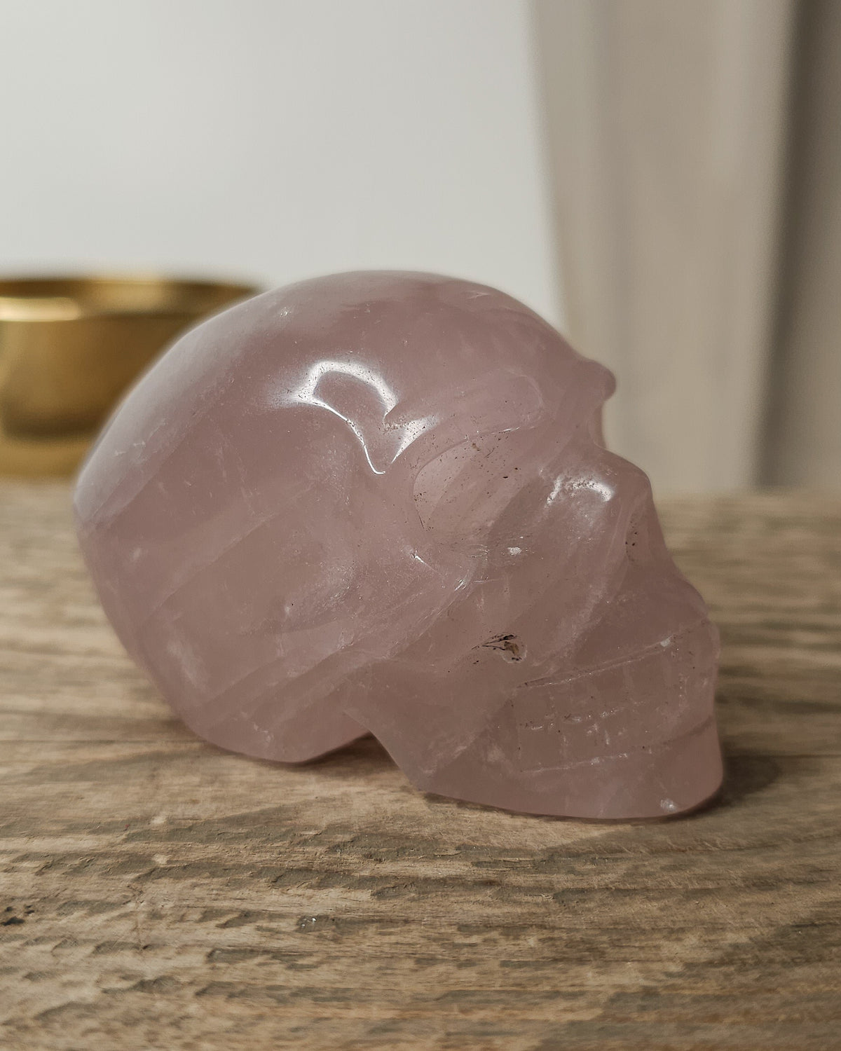 Rose Quartz crystal skull carving with soft pink tones and natural cloudy patterns, polished finish, displayed as a decorative crystal piece.