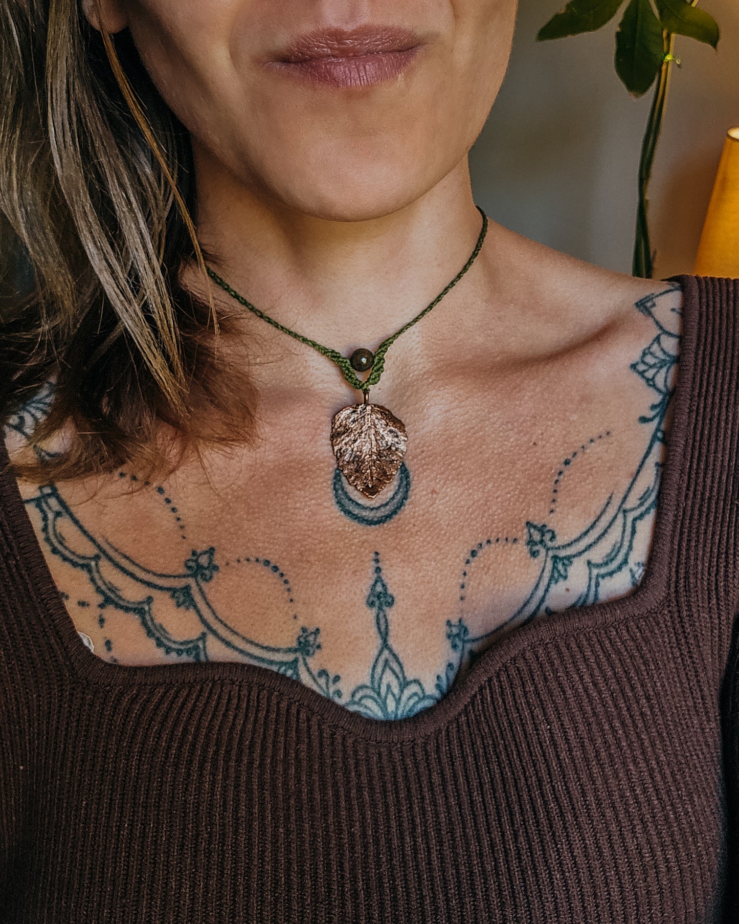 Woman wearing Nettle Spirit Scottish Botanical Amulet, a copper electroformed dead nettle leaf necklace featuring a natural Brown Jasper bead.
