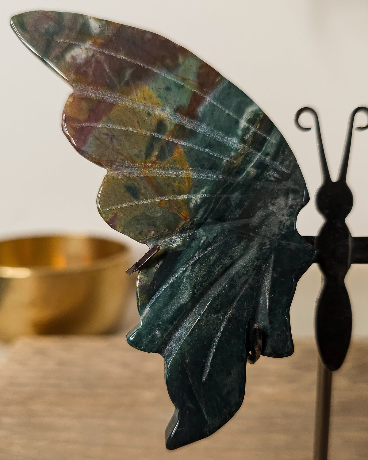 Jasper butterfly wings on a black metal stand, featuring deep green, earthy brown and golden natural patterns.