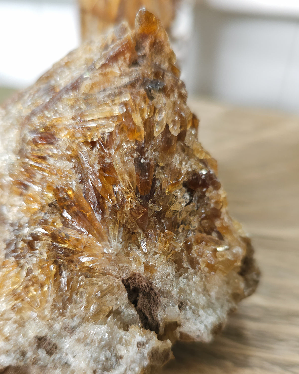 Close-up of a Mineral Amber Calcite specimen on a wooden surface with a blurred indoor background